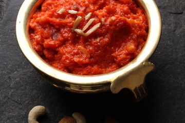 Gajar ka halwa is a carrot-based sweet dessert pudding from India. Garnished with Cashew almond nuts and Served in brass bowl.