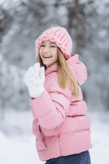 Happy cheerful caucasian girl walking in winter snowy park. Beautiful happy young girl posing outdoors