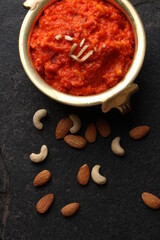 Gajar ka halwa is a carrot-based sweet dessert pudding from India. Garnished with Cashew almond nuts and Served in brass bowl.