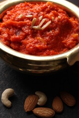 Gajar ka halwa is a carrot-based sweet dessert pudding from India. Garnished with Cashew almond nuts and Served in brass bowl.