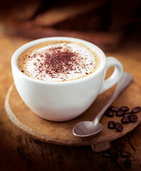 white cup with teaspoon on on wooden stand