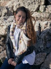 Vertical shot of a young caucasian female posing against the stone wall