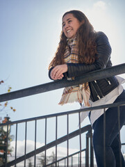 Shallow focus shot of a happy young female smiling and leaning on a railing