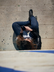 Overhead shot of a young female using her smartphone while sitting on the ground
