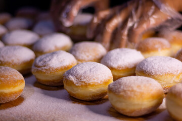 hand pouring icing sugar on doughnut