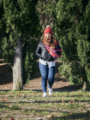 Vertical shot of a young female in winter clothes walking in the park