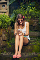 Obraz premium Caucasian young woman using modern smartphone in oriental garden.