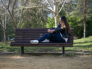 Young caucasian female sitting on a wooden bench in the park