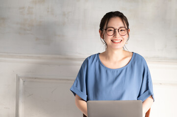 パソコンを使いながらリモートワークのミーティングをする美しい眼鏡の若い日本人女性　左にコピースペースあり - obrazy, fototapety, plakaty