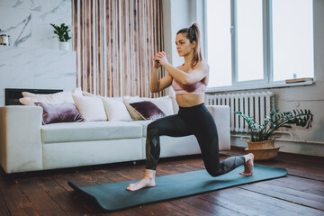Young fit woman do frontal lunges or squat exercise indoors in living room. Online indoors workout....