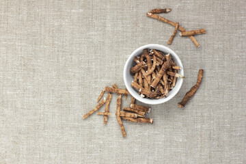 Dandelion herbal roots in a bowl flat from above on linen textile, overhead top view of wheat-grass, closeup, copy space, natural medicine and vegan protein source ingredient concept