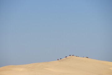 touristes marchant en haut sur la crête de la dune du Pilat ave un ciel bleu