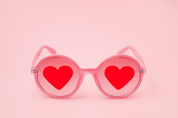 Pink sunglasses with red hearts on glasses close-up in the center of the frame for Valentine's Day....