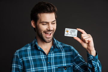 Delighted unshaven guy exclaiming while posing with credit card