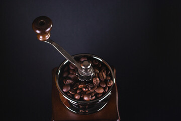 Coffee grinder with coffee beans on black background
