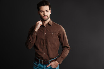 Brunette handsome unshaven guy posing and looking aside