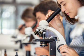 High school girl looking through microscope at school