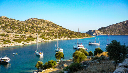 charter yacht sail boats anchored in rocky bay with blue sky and sea on holiday cruise. © William Richardson