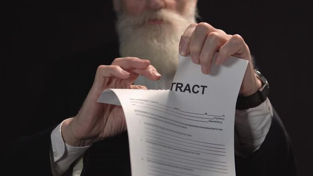 Serious bearded businessman tearing paper with contract sign, bad conditions