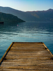 wooden pier on flat sea with mountain background