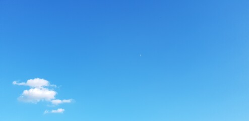 Blue sky background with a small group of tiny clouds in the left lower corner