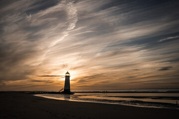 Lighthouse standing in pool of water stunning sunset sunrise reflection reflected in water and sea steps up to building north Wales seashore sand beach still water orange glow golden hour blue hour