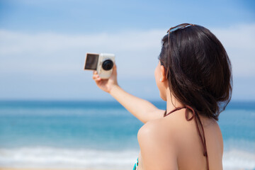 An Asian woman wearing a bikini Takes pictures of herself during her vacation on the beach.selective focus at her