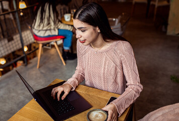Fototapeta na wymiar Portrait of young woman using laptop in coffee shop.