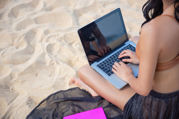 Young asia woman using a laptop computer on a beach. Freelance work concept and holiday working or money passive income