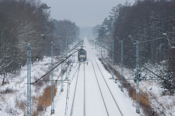 Lokomotywa elektryczna jadąca po torach pokrytych śniegiem. © boguslavus