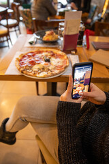 Woman hands taking picture, with smartphone, of the food served in the restaurant