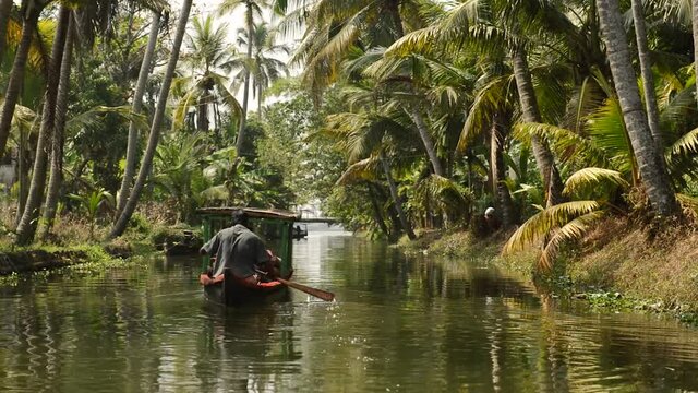Small tourist boat on beautiful canals and lagoons of Kerala. Landscape from swimming boat on water with palm trees, Kerala, Alappuzha backwaters on a sunny day