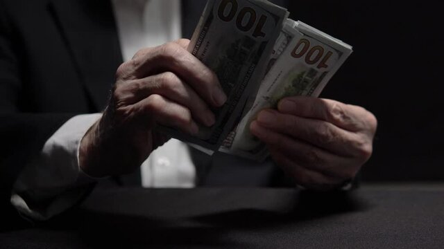 Close up hands oldster counting dollars, depositing money at high interest rate
