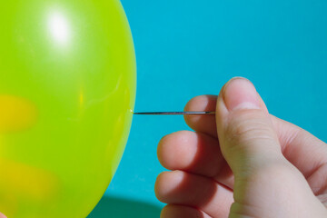 Pop the balloon with a sharp needle. Hold the sewing needle in your hand.