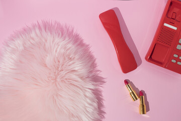 Bright red retro design handset phone with red and pink golden lipsticks and pastel pink faux fur....