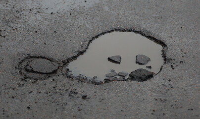 A water-filled pothole in the road surface