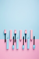 Set of professional mascara on pastel pink and blue background with copy space for text. Minimal make up, beauty, fashion, party and shopping concept. Cosmetic or beauty salon layout. Flat lay.