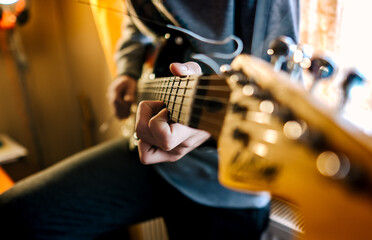Fototapeta premium Male hands playing electric solo guitar with closeup photo. Learning musical instrument, music shop or school, blues bar or rock cafe, having fun enjoying hobby concept
