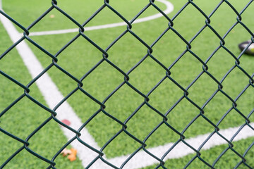 Fototapeta premium Fence netting close-up on a background of a soccer field.