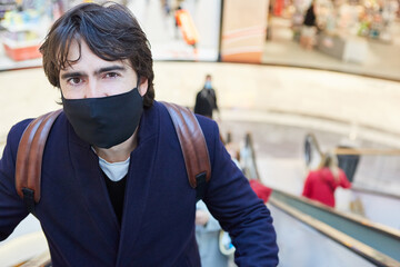 Man with face mask on an escalator in the shopping center