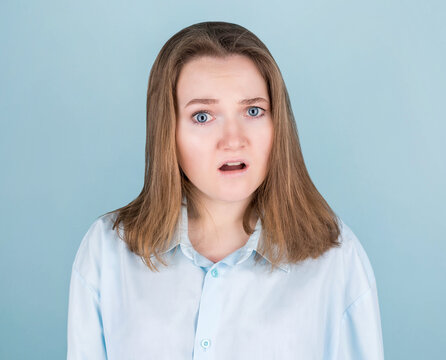 Young woman very surprised looking at the camera. Surprise and shopping concept on blue background.