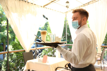 Fototapeta na wymiar Waiter serving beverages in restaurant. Catering during coronavirus quarantine