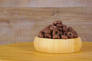 Chocolate flakes in wooden bowl.  Nutritious breakfast. Chocolate flakes. Healthy breakfast. Copy space.