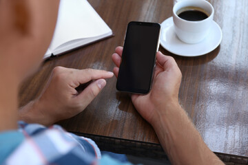 Man with smartphone at table in cafe, closeup