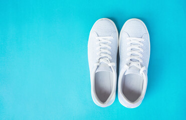 White female sneaker on blue background.