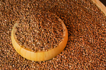 Seed background.  Buckwheat grains product. Raw buckwheat in wooden container top view.  Roasted buckwheat kernels. Marketing, advertising use. Studio shot. Healthy organic food diet concept.