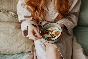 In the hands of the child a plate of porridge sprinkled with nuts