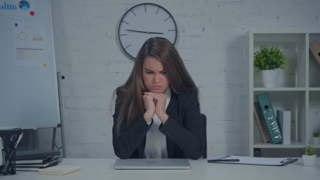 displeased businesswoman turning off laptop and puffing cheeks in office