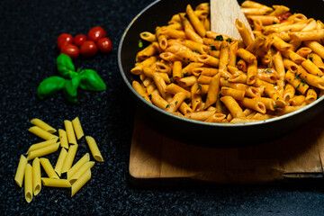 Penne pasta amatriciana in tomato sauce and cheese decorated with basil, top view.
