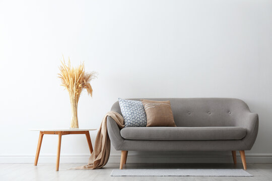 Grey Sofa With Pillows Near White Wall In Stylish Living Room Interior